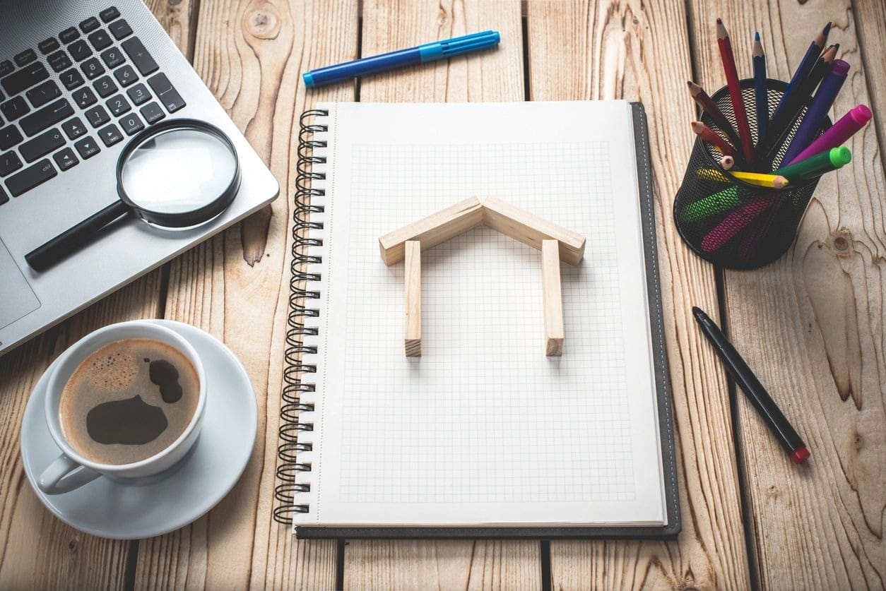 A notebook with a wooden house on top of it.